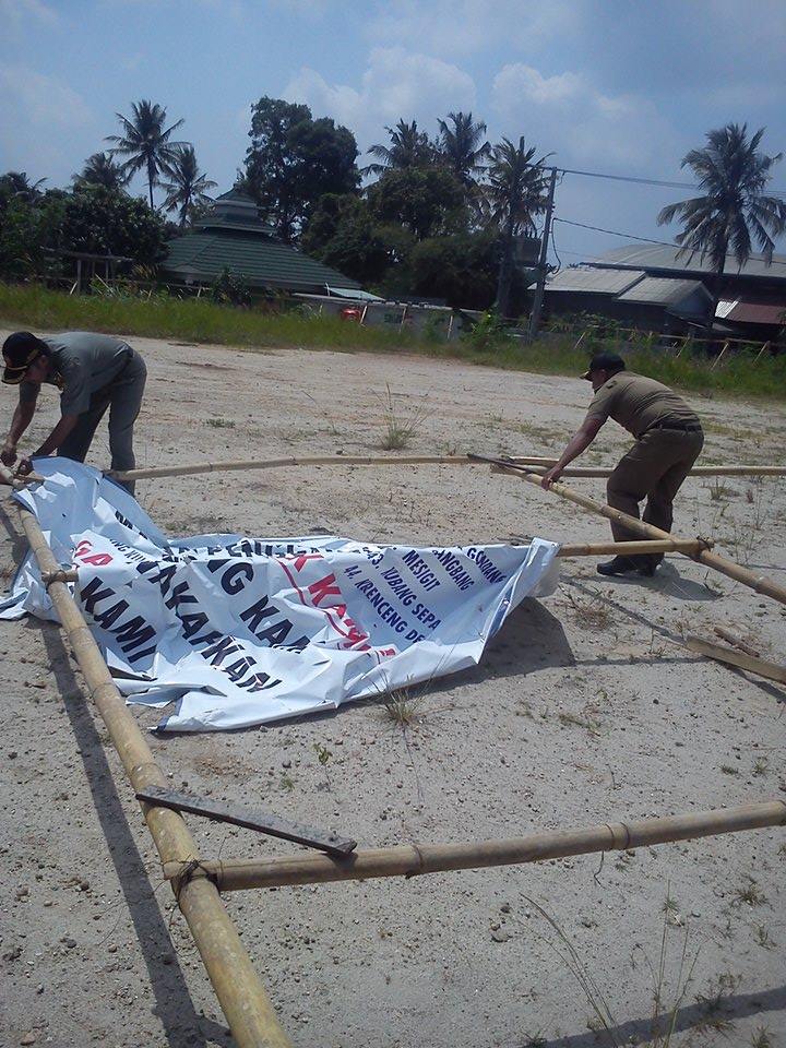 Pengelola yayasan makam balung  dibantu Satpol PP Kecamatan Citangkil mencabut spanduk penolakan Rusunawa oleh warga setempat