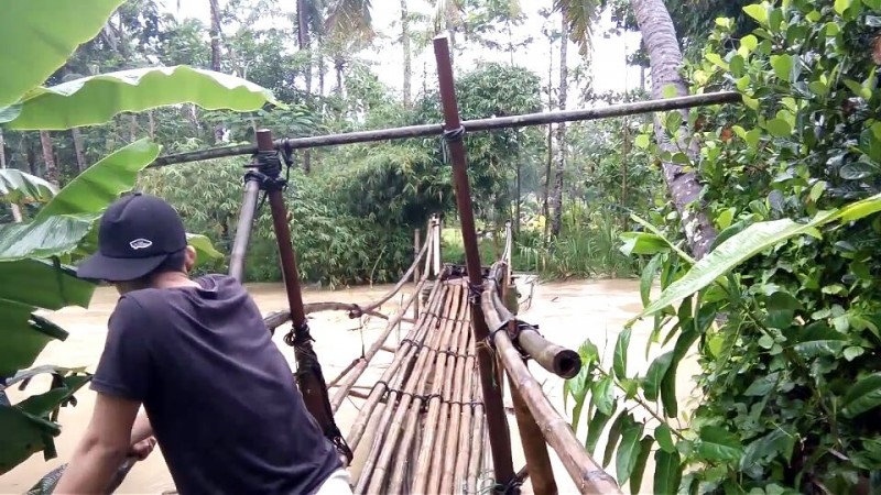 Seorang Warga Saat Hendak Melintas Di Jembatan Bambu Yang Rawan Ambruk. (Foto, BidikBanten)